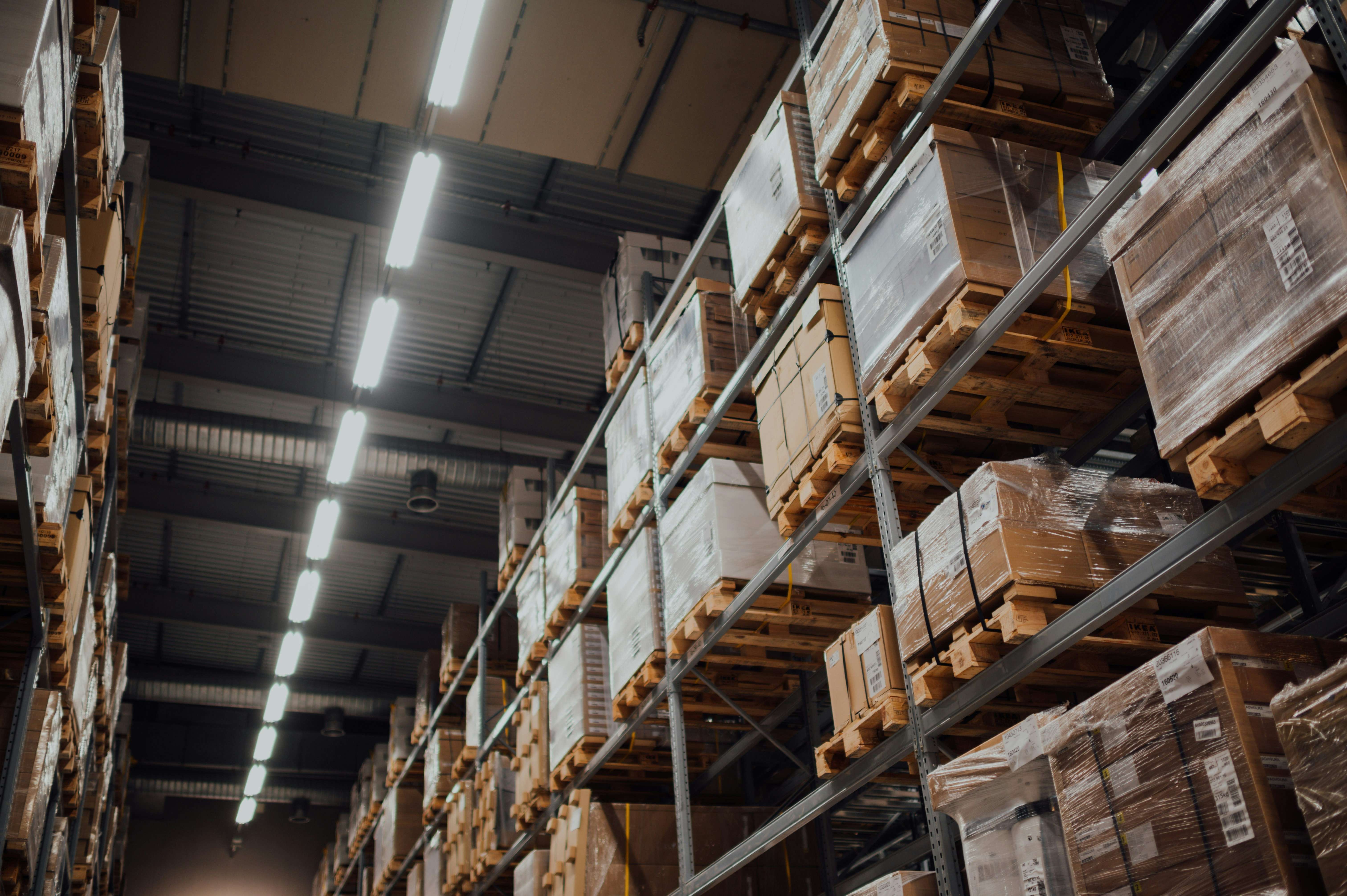 Interior view of a warehouse with high shelves of stacked boxes.