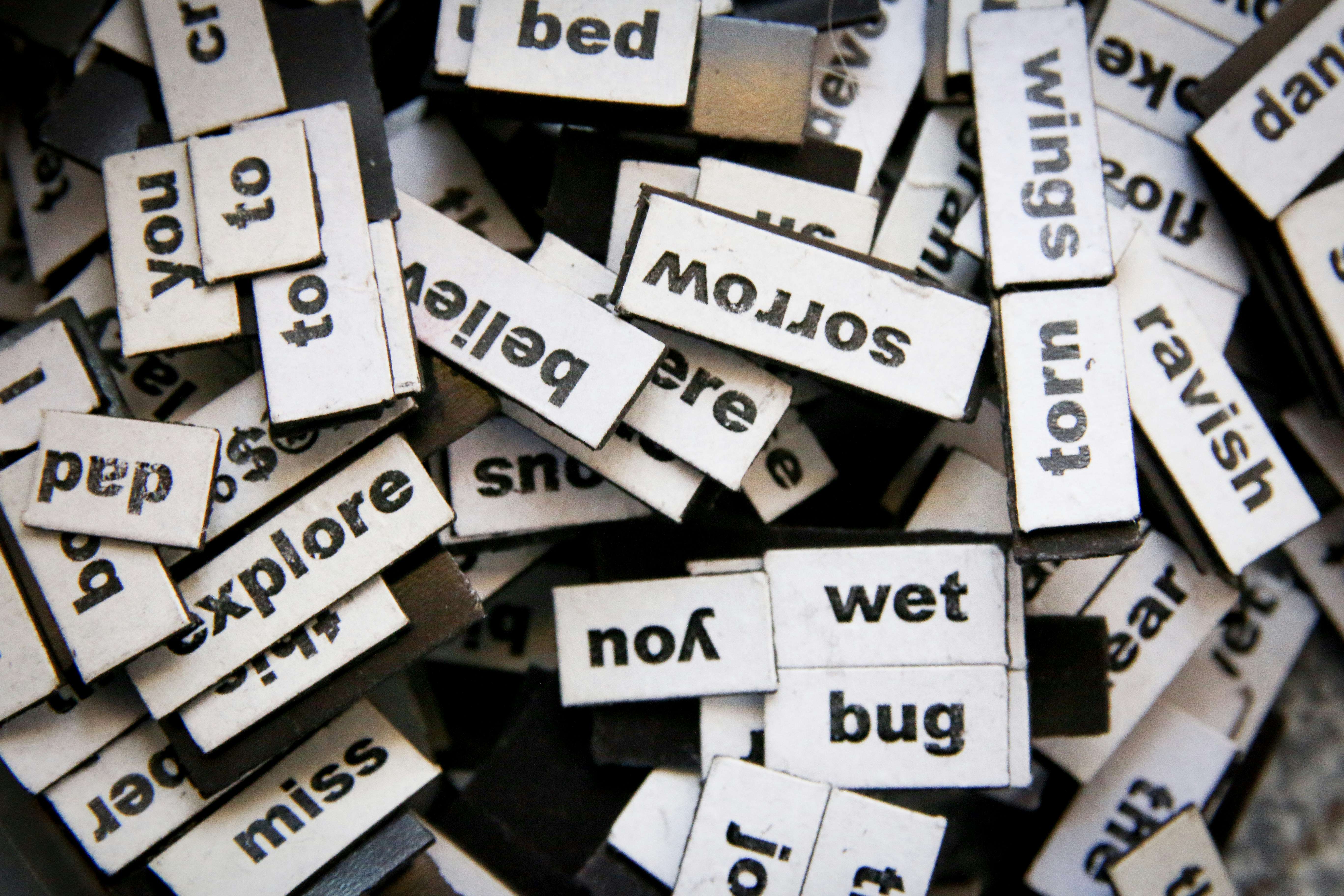 A pile of wooden tiles with various words on them.