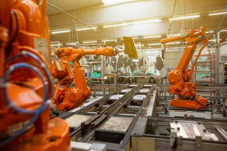 Reihe von orangen Industrierobotern, die an einer Montagelinie in einer Fabrik arbeiten.