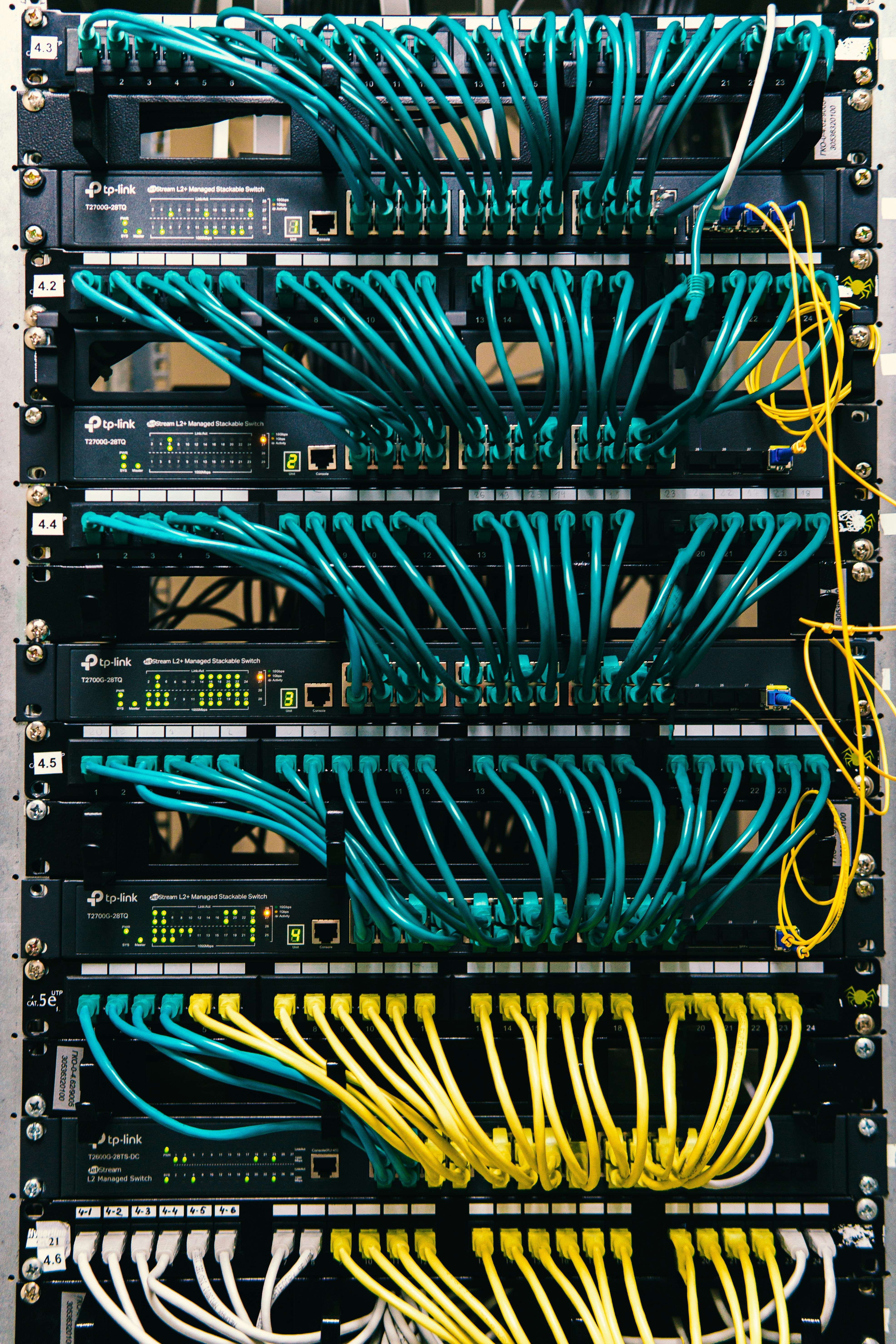 Network rack with multiple switches and colorful ethernet cables.